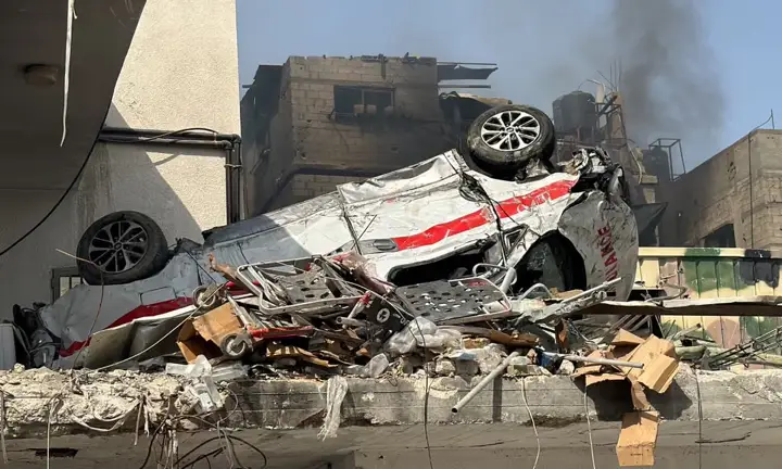 destroyed-ambulance-in-front-of-bombed-houses